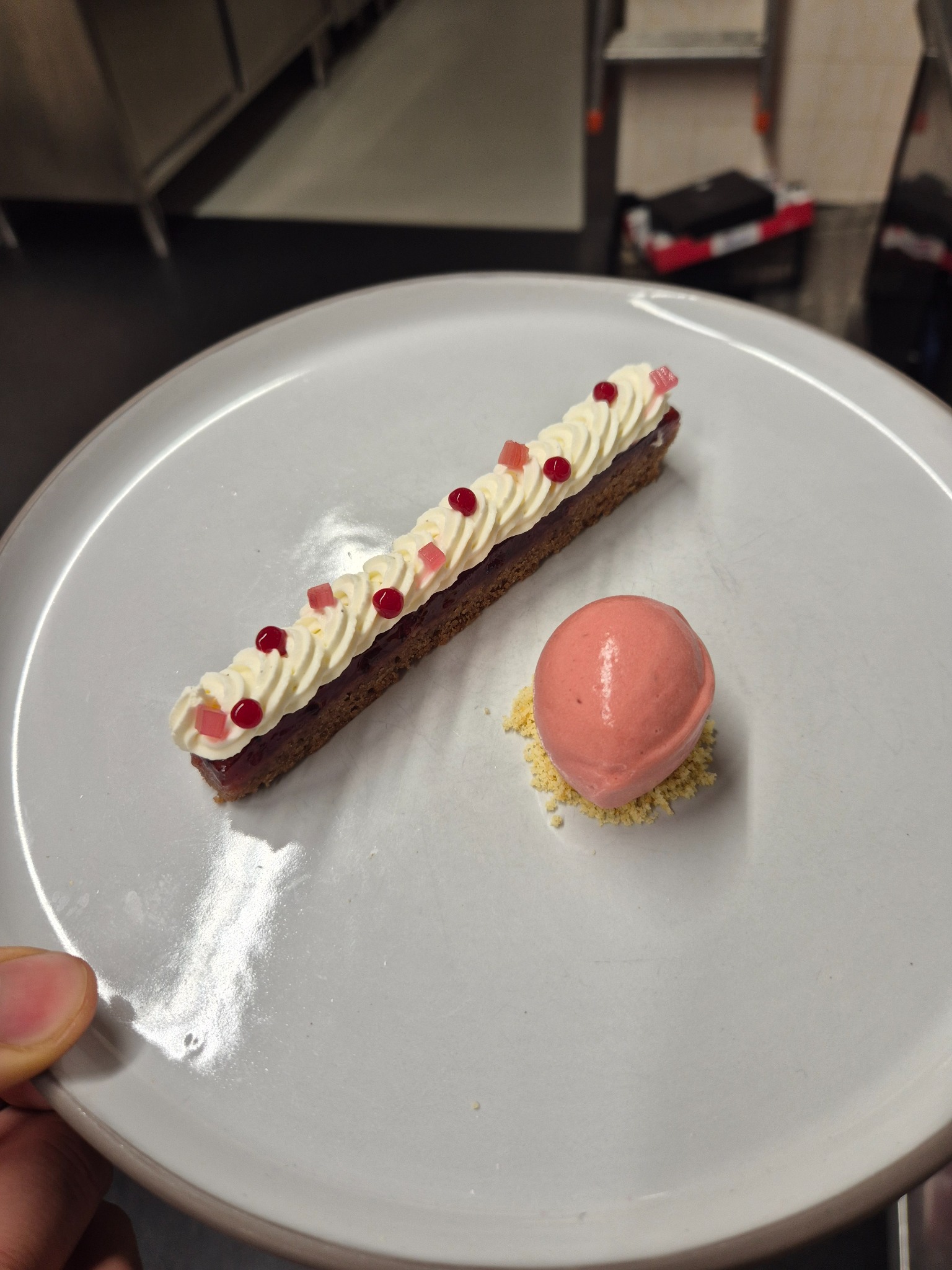 La Linzer di Lorenzo: dessert allungato con crema e sorbetto rosa, fotografato in cucina